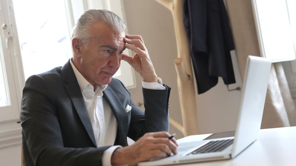 Stressed businessman holds his head while at his computer