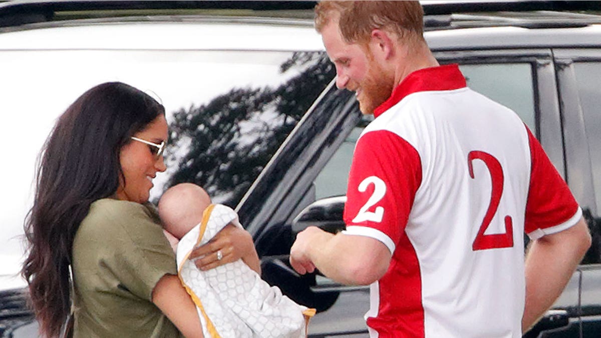 Prince Harry admiring Prince Archie as Meghan Mark;e holds him