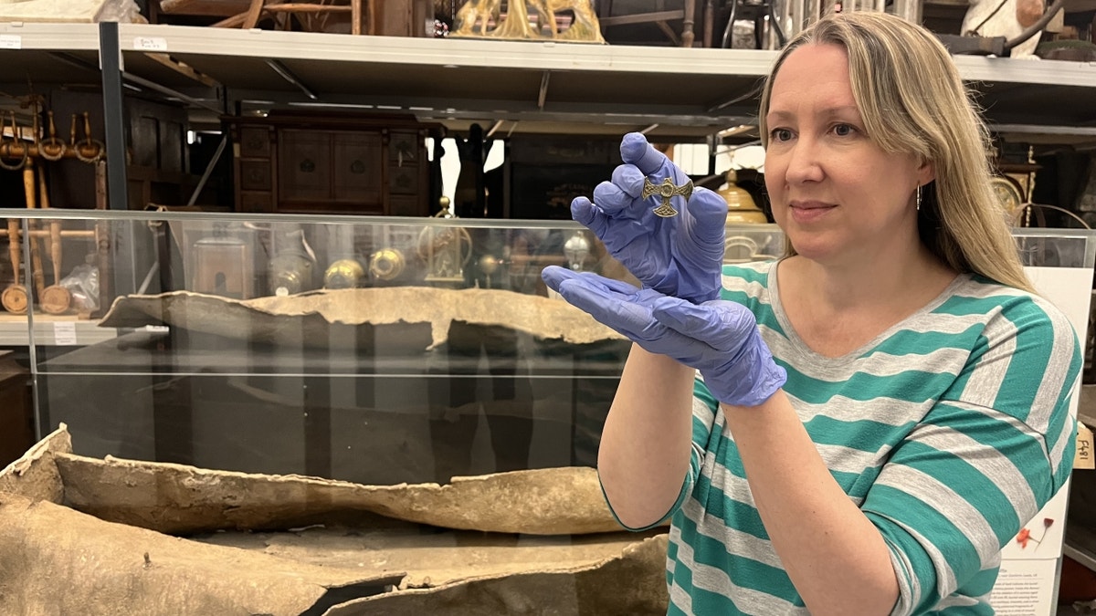 Wide shot of curator holding broken cross