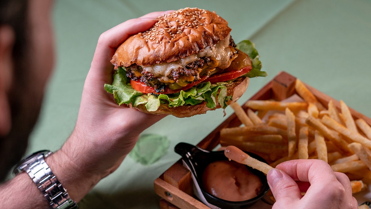 Man holding a tasty hamburger: new tests may be able to detect junk food consumption from blood and urine samples