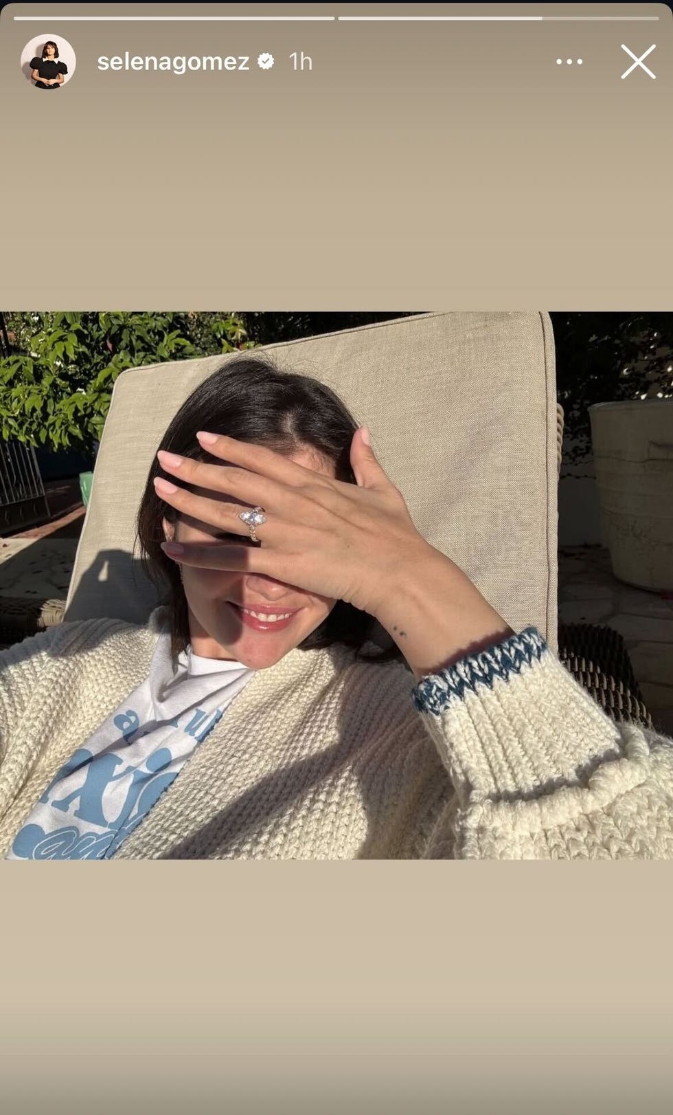 person covering their face with a hand while smiling wearing a cozy sweater