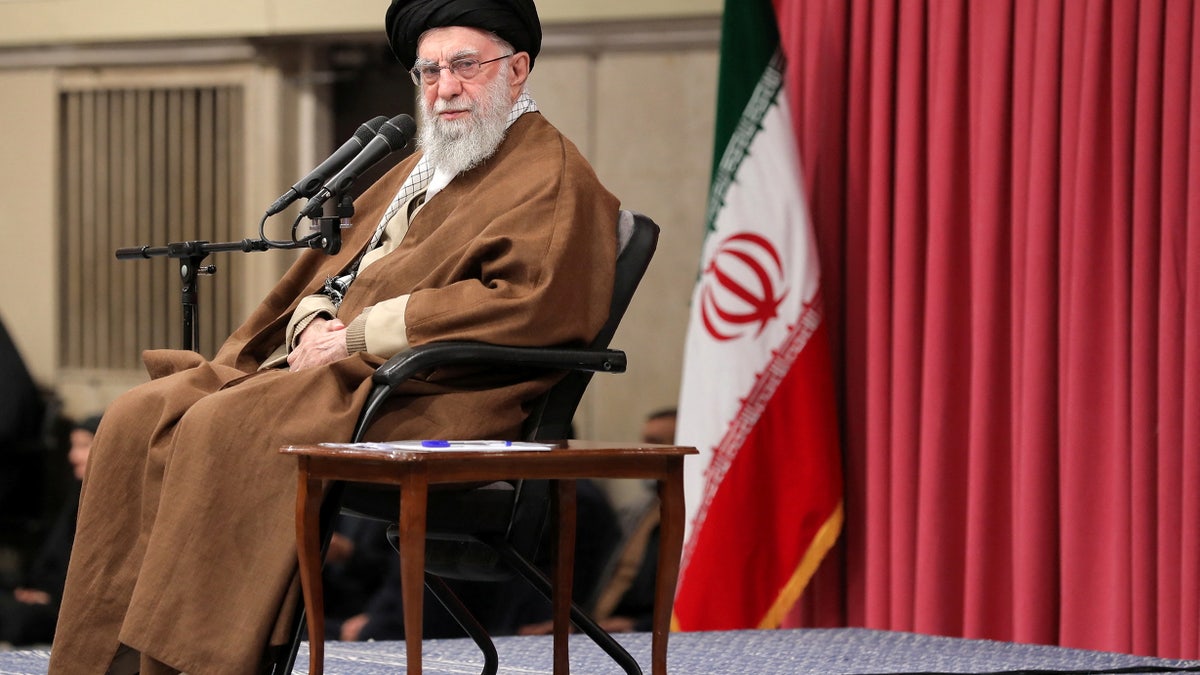 Khameini in chair, Iran flag behind him