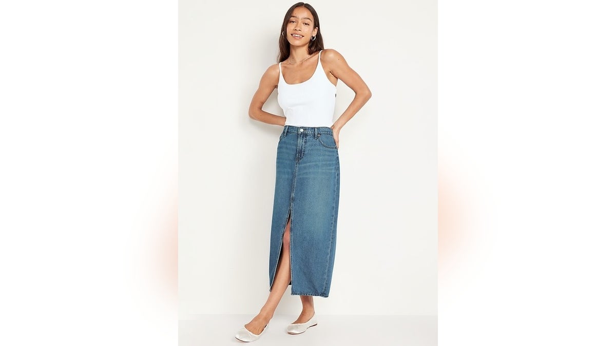 A model wearing a denim skirt and white top.