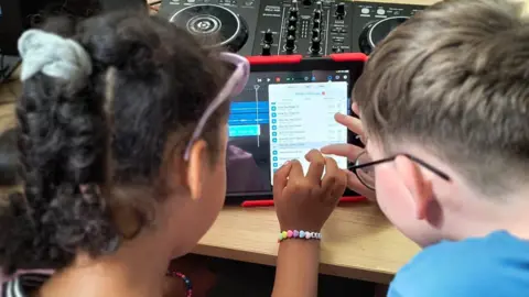 YACAD Two children working on a tablet computer, doing some sound editing.
