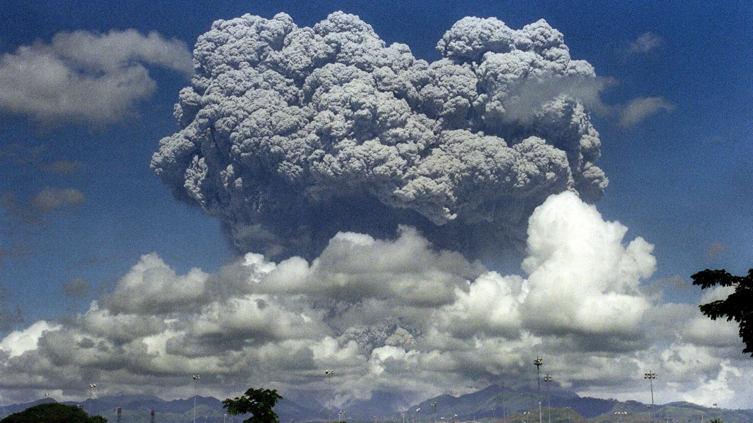 Grey cauliflower like cloud and white bubbles of cloud above a stratovolcano