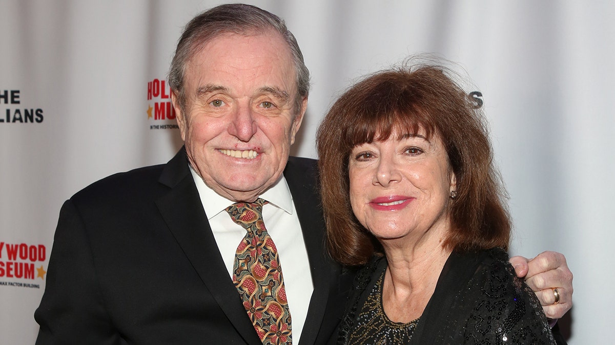 Jerry Mathers in a suit and tie smiling next to his wife