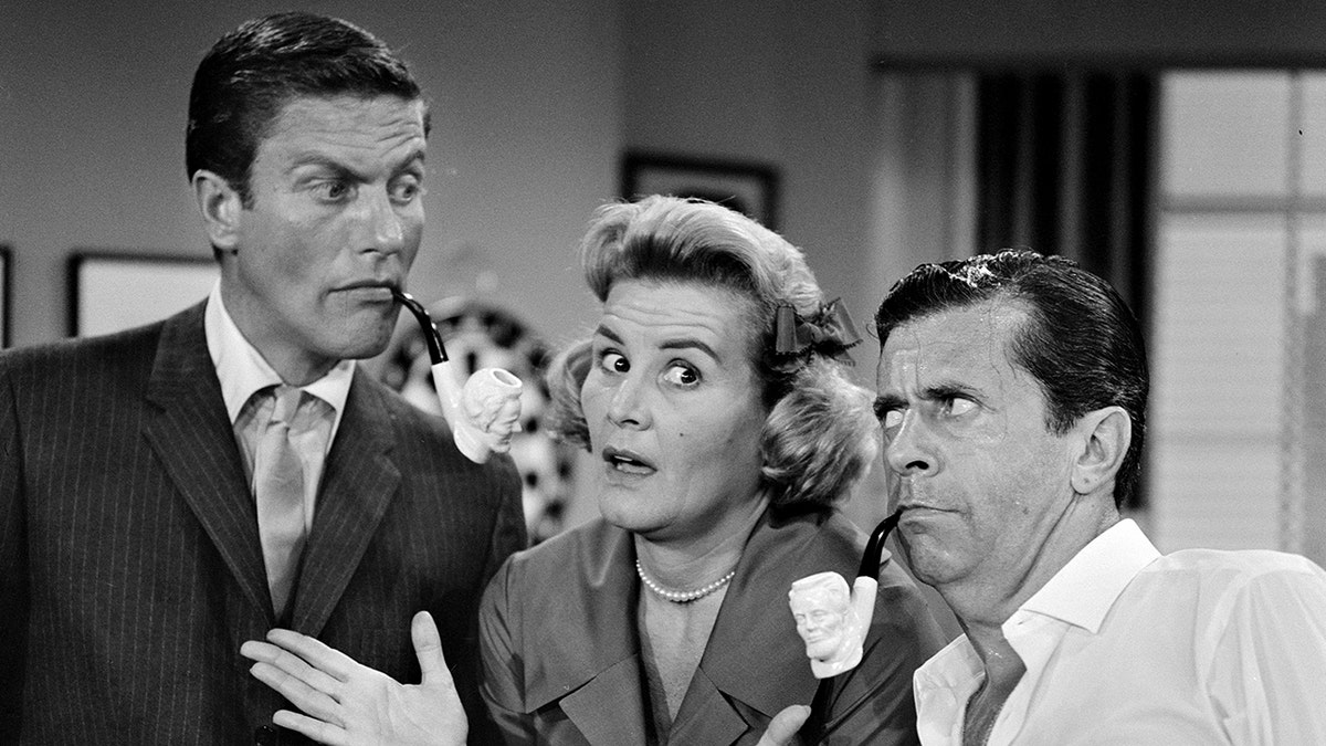 Rose Marie shrugging her asrms as Dick Van Dyke and Morey Amerstam make funny faces