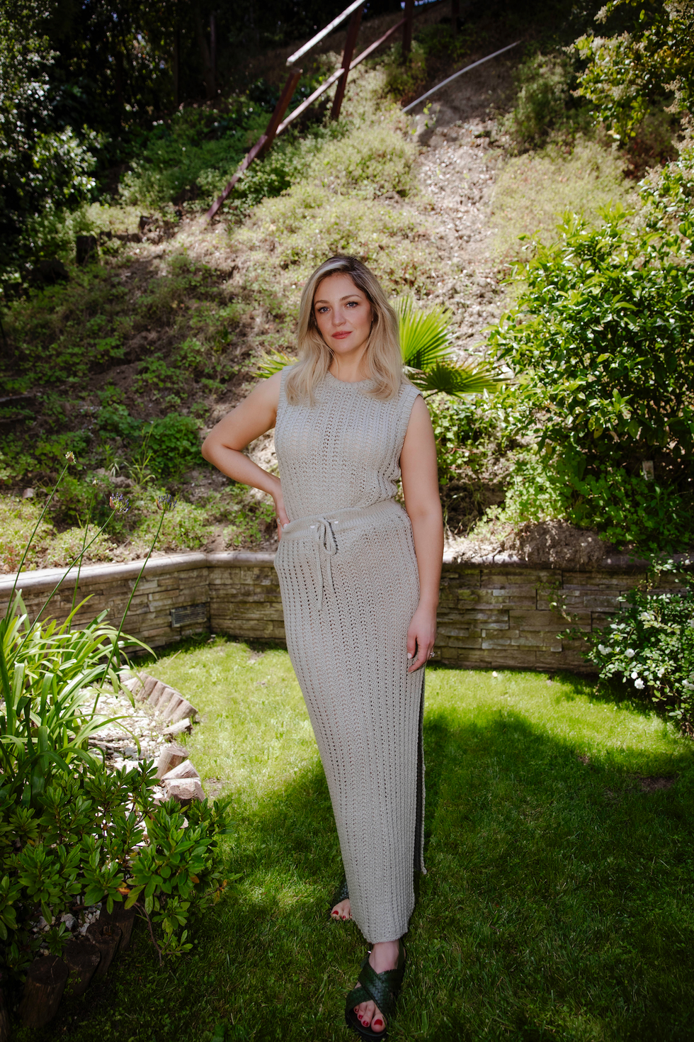 abby elliott wearing a light knitted dress in a garden
