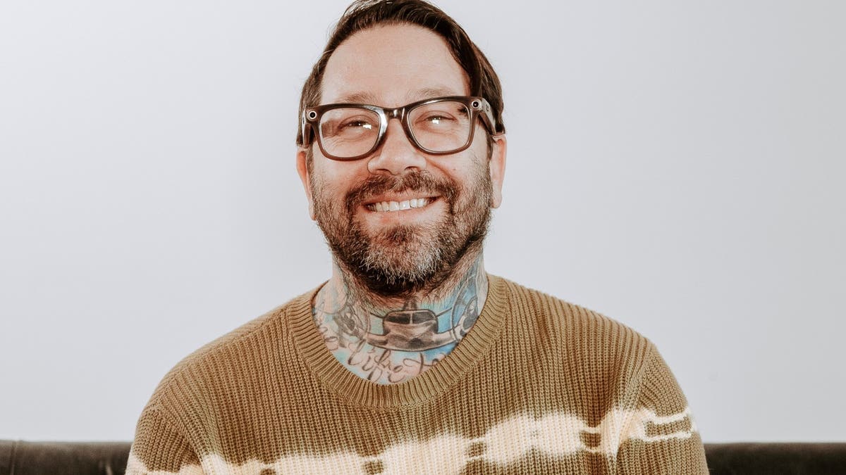 Dave Shapiro wears khaki sweater with glasses