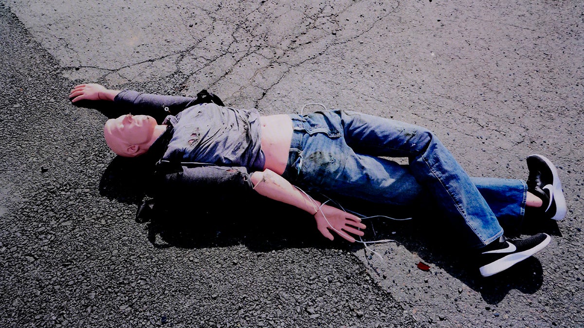 An image of a "Rescue Randy" mannequin is displayed sprawled out on pavement in clothing similar to what John O'Keefe was wearing when he died