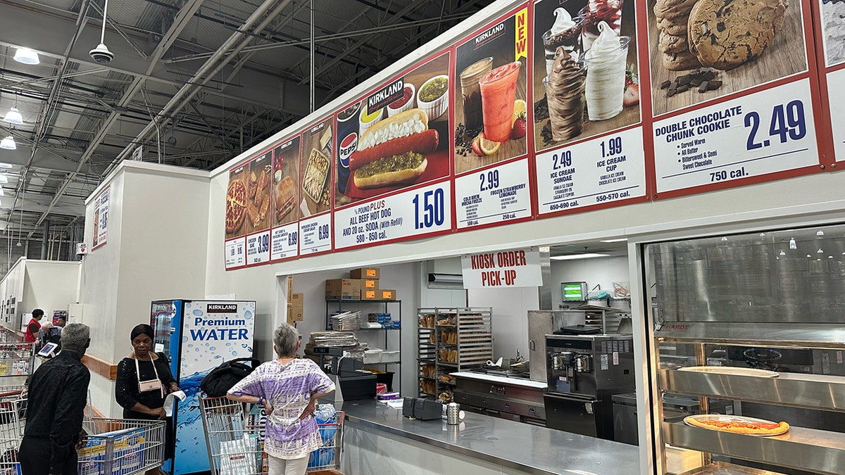 Costco members wait near the food court counter below a sign for the new frozen strawberry lemonade.