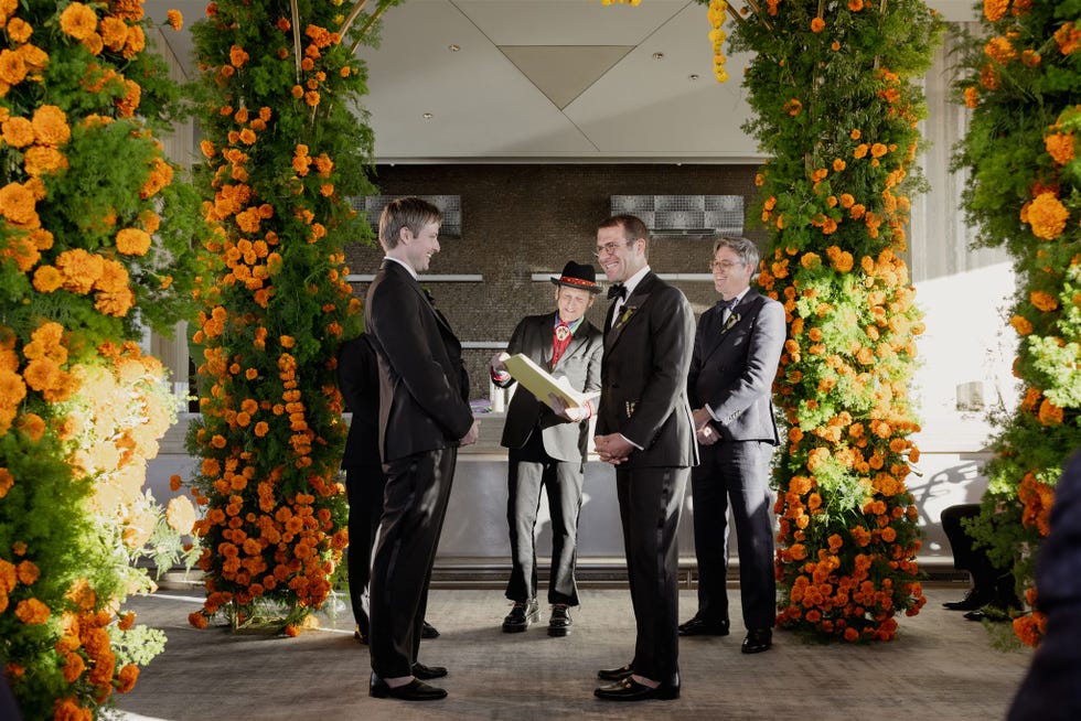 ceremony featuring two individuals exchanging vows under a floral arch