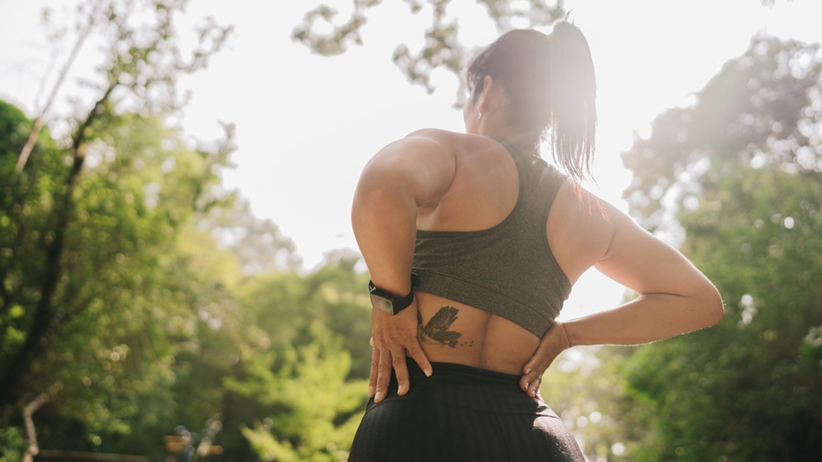 woman holding lower back outside