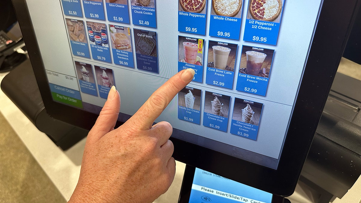 A woman's hand orders the new frozen strawberry lemonade drink from a Costco food court kiosk.