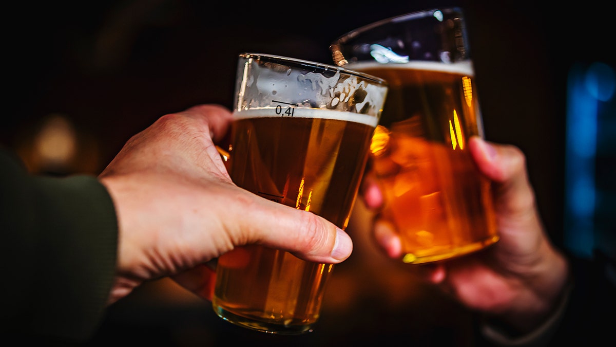 Hands holding craft beer glasses come together for a toast.