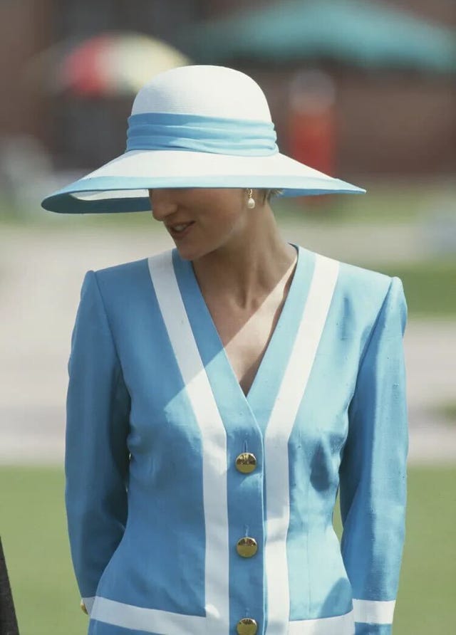 a person wearing a blue outfit with white stripes and a large sunhat