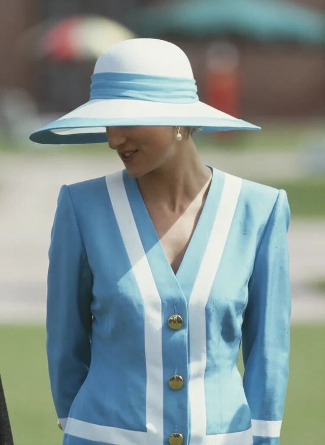 a person wearing a blue outfit with white stripes and a large sunhat