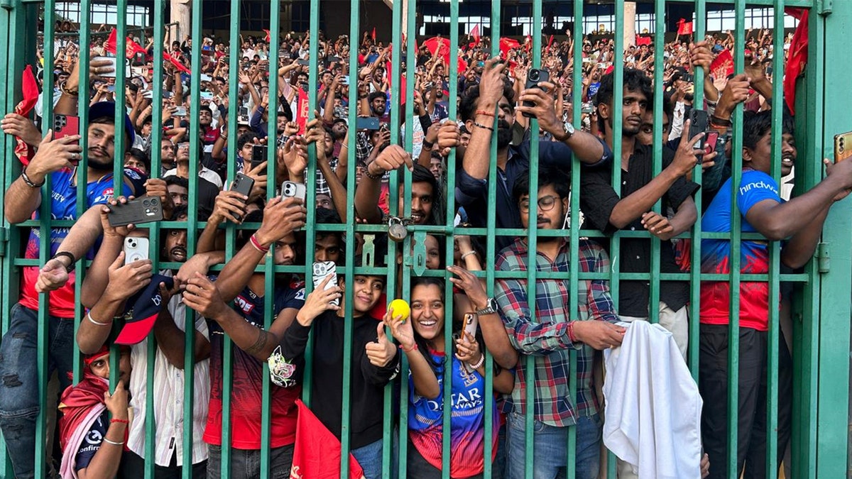 A crowd of cricket fans behind a gate