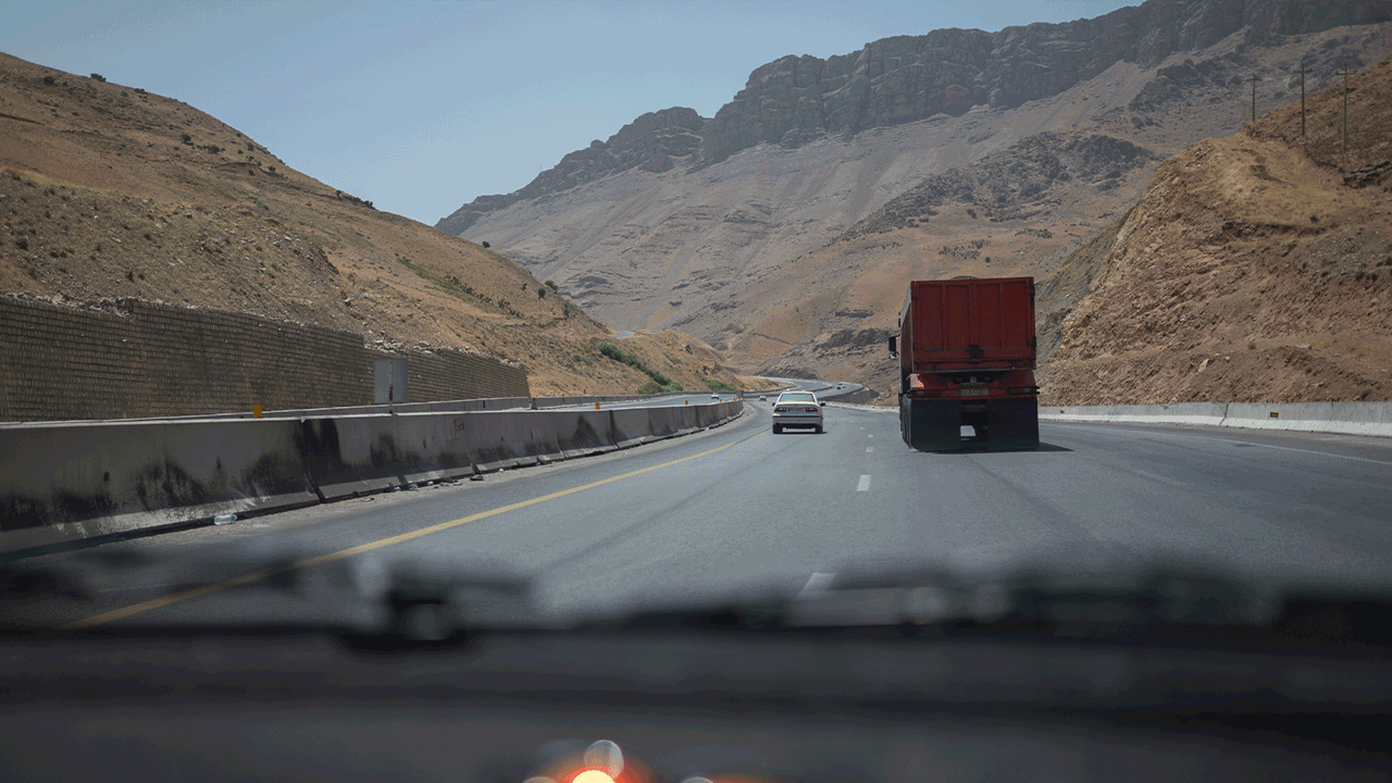 Cars drive on highway through arid mountains
