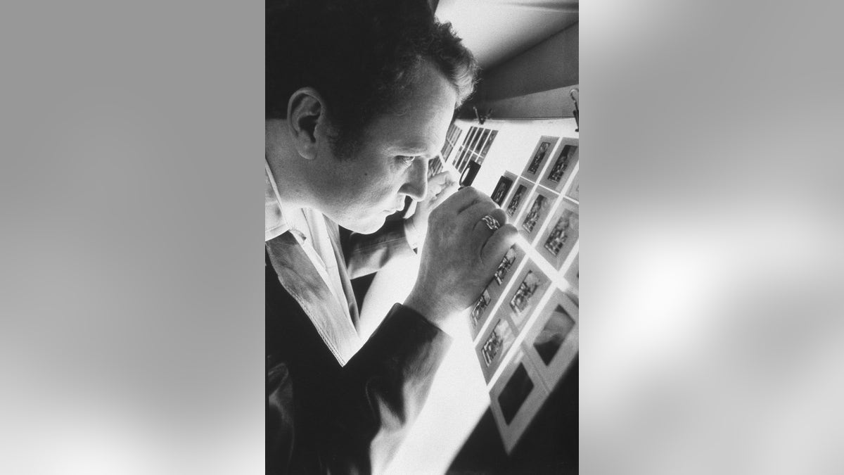 A young Larry Flynt looking at photos in a dark room.