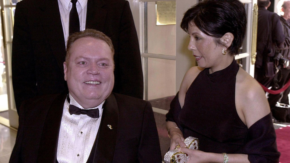 Liz Flynt looking down at Larry Flynt, who is smiling and wearing a tux.