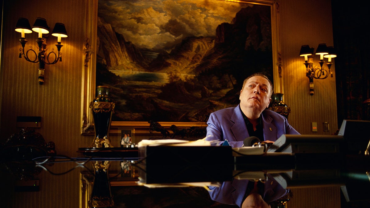 Larry Flynt wearing a blue vest and looking up from his office.