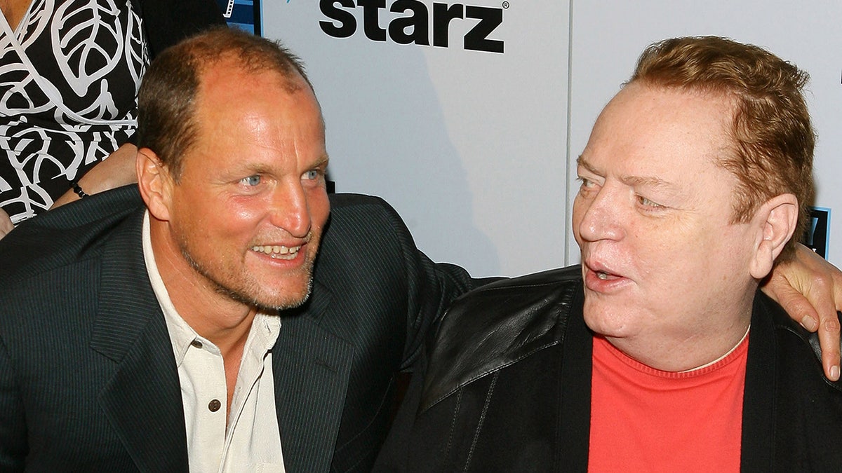 Woody Harrelson and Larry Flynt sharing a warm embrace and smiling.