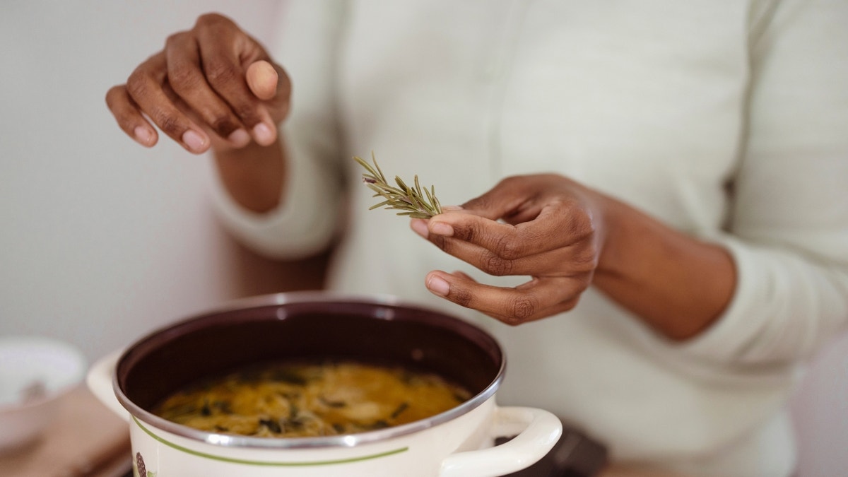 Woman cooking dish with rosemary
