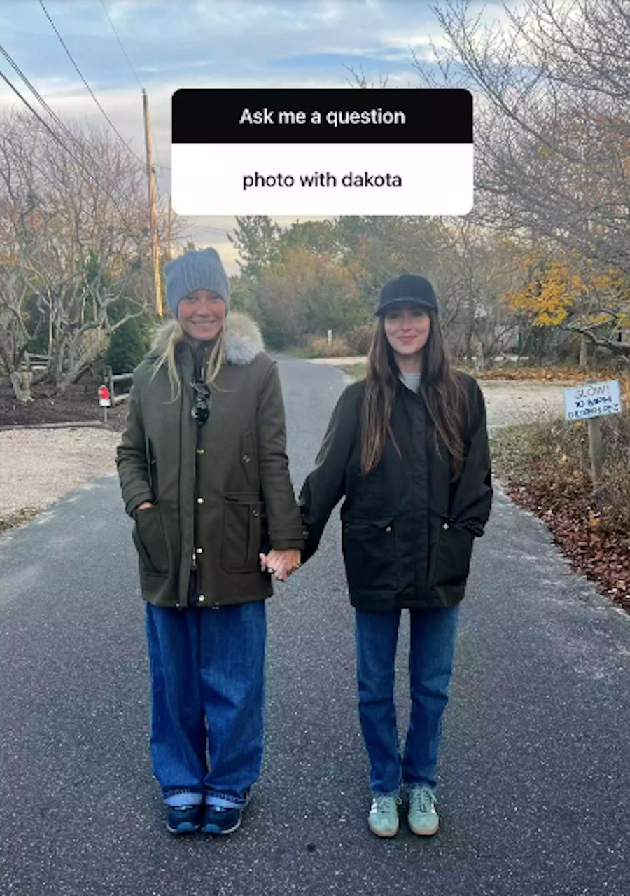 a man and woman standing on a road with trees and a sign