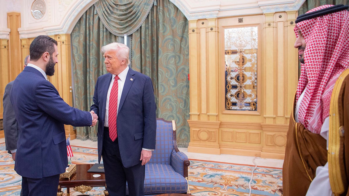 In this photo released by the Saudi Royal Palace, interim Syrian President Ahmad al-Sharaa shakes hands with President Donald Trump in Riyadh, Saudi Arabia on May 14. At right is Saudi Crown Prince Mohammed bin Salman. 