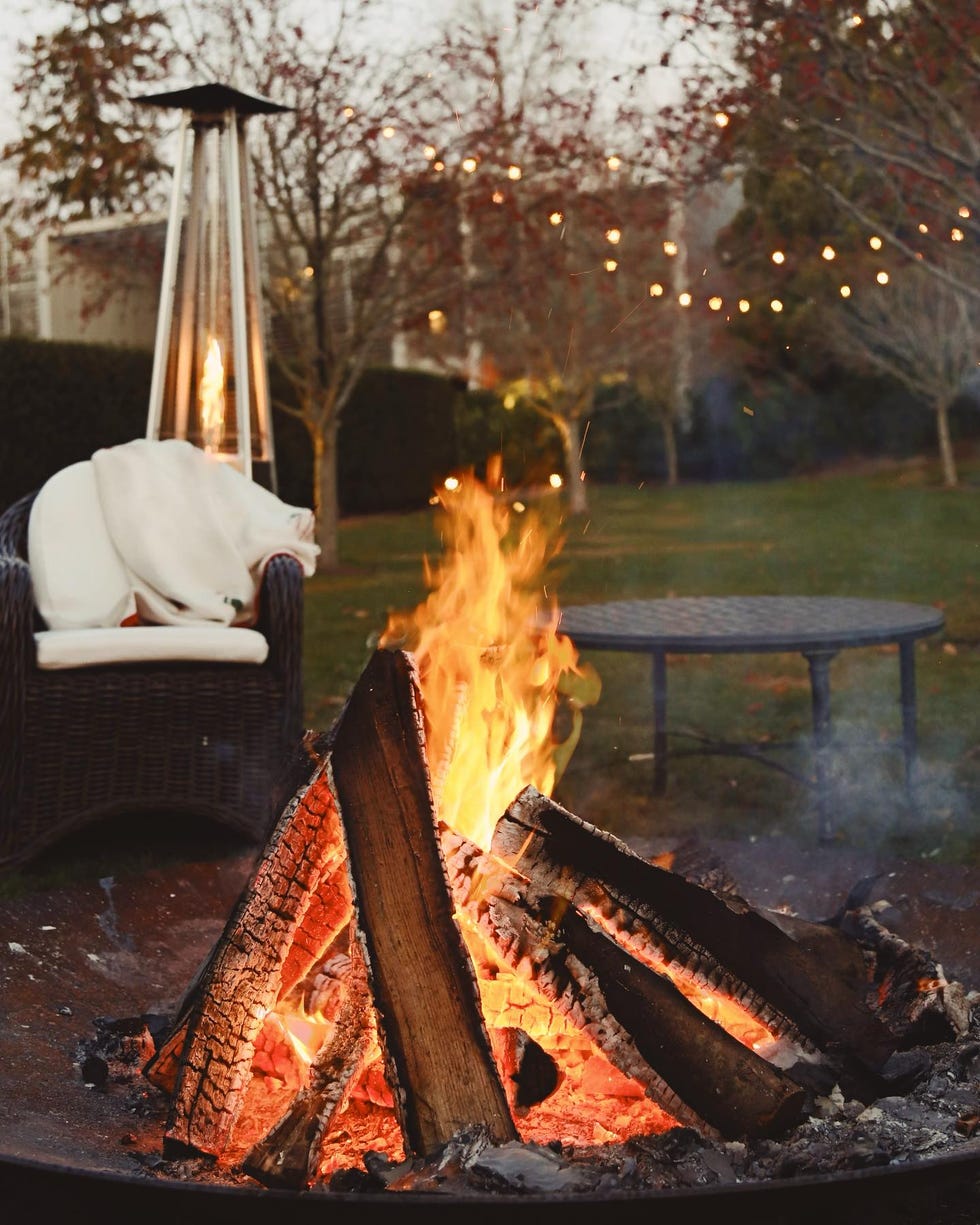 fire pit with burning wood and a nearby chair