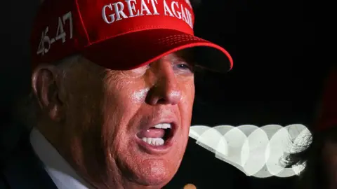 Getty Images US President Donald Trump wearing red cap with 45-47 seen on the side and GREAT AGAIN seen on the front