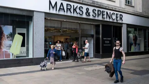 Getty Images Marks and Spencer store in Swansea with people walking in and out of the store and a man walking in front of it