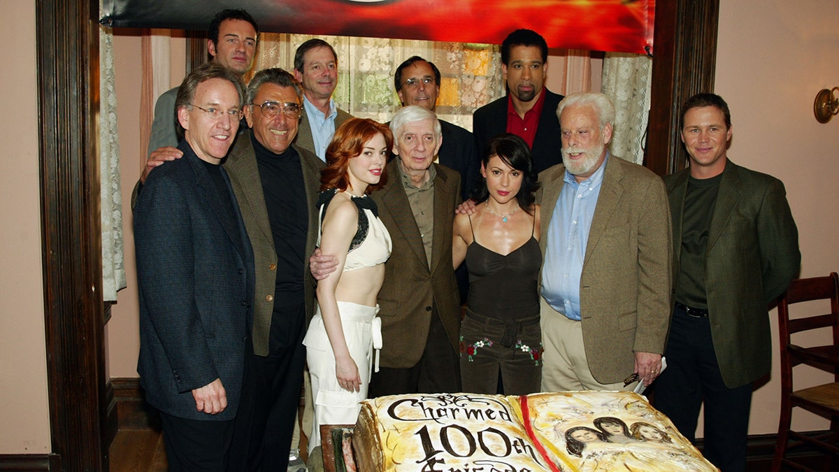 Julian McMahon smiling with the cast of "Charmed" in front of a cake.