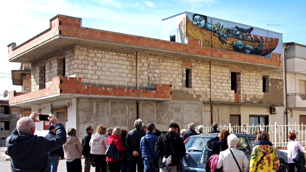 People gathered in Stornara, Italy to admire and take pictures of a mural on the side of a building