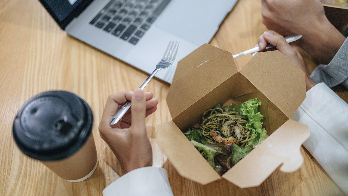 Man eating salad while working at keyboard