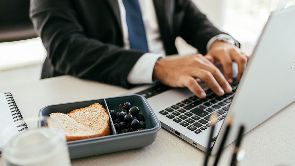 Man typing at keyboard with lunch