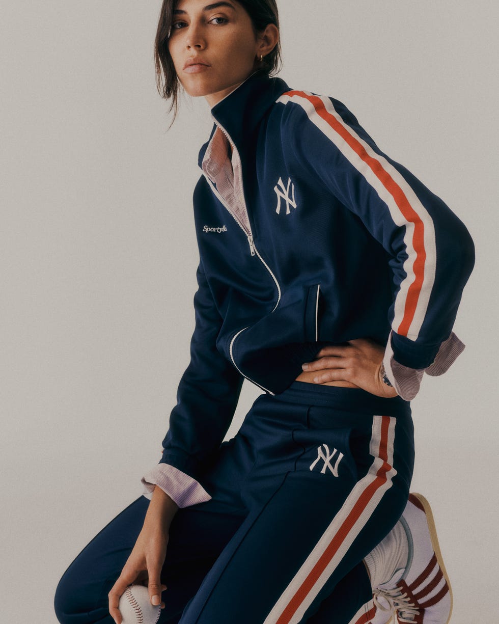 athletic outfit featuring a zipup jacket and matching pants with a baseball in hand