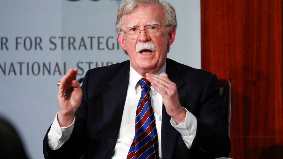 Trump national security adviser John Bolton speaks in a black suit with a blue striped tie