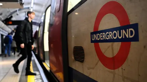 Shutterstock File image showing a man dressed in black boarding a London Underground Tube carriage, with a close-up of the underground roundel logo on the carriage