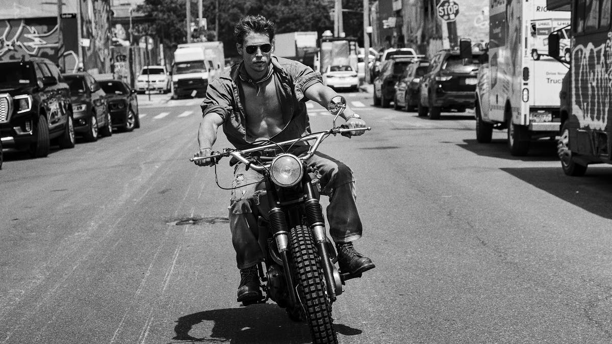 Austin Butler is seen in a black and white photo riding a motorcycle