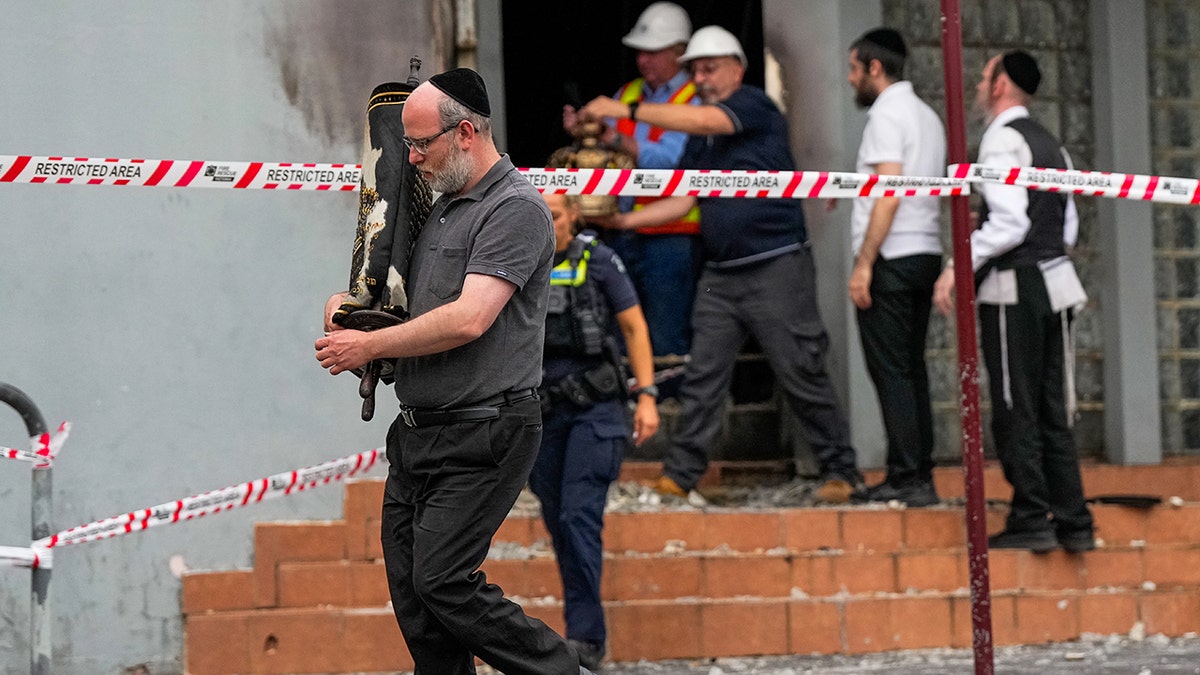 Man carries Torah scroll out of a synagogue that was attacked