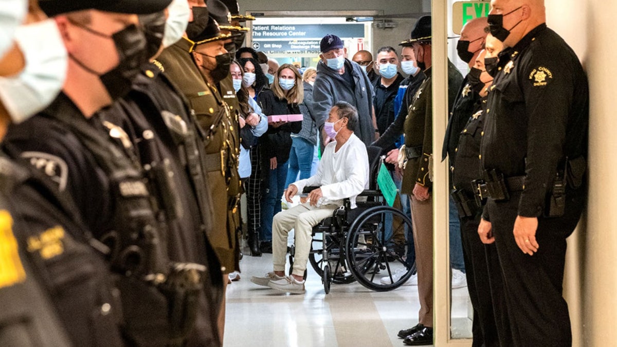 David Easterly in wheelchair as law enforcement officers line hallway of hospital
