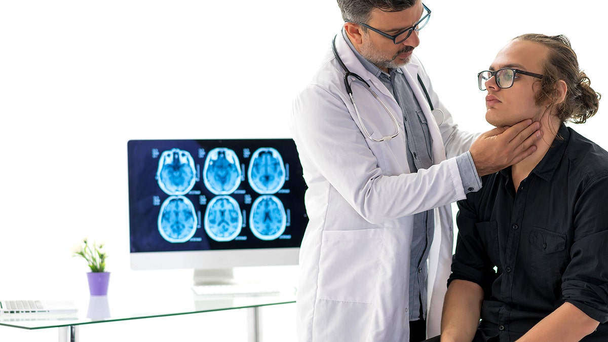 Doctor examining patient's throat with brain scans behind the pair.