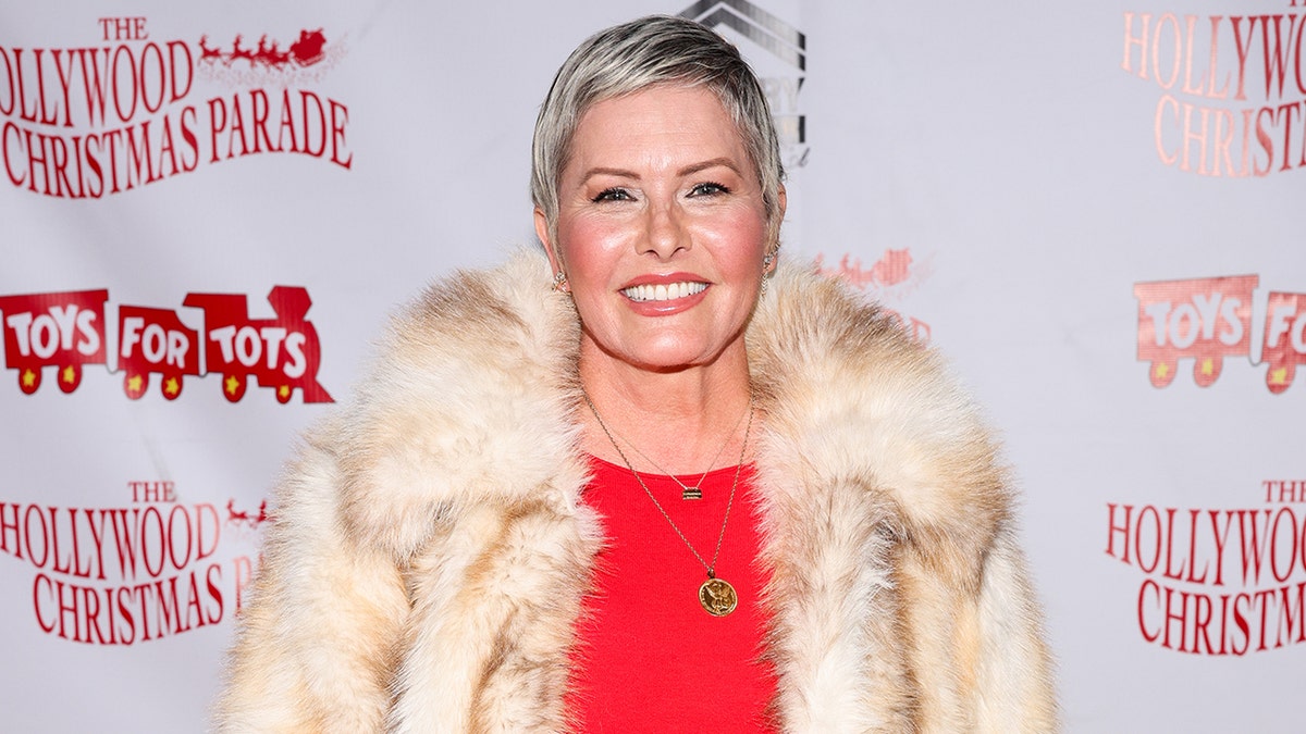 Nicole Eggert smiles while posing on a red carpet.