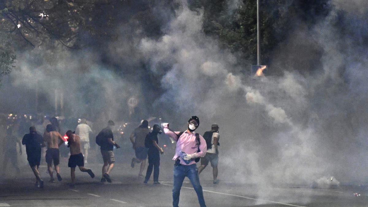 Demonstrators stand in clouds of tear gas during anti-government protesters in Belgrade on August 16, 2025. Clashes erupted in two Serbian cities in fifth night of unrest late on August 16, 2025.
