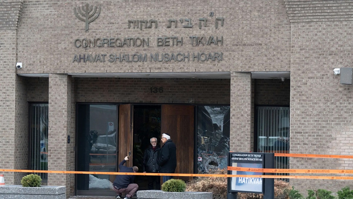 A man fixes the lock of the doors of Congregation Beth Tikvah as police investigate an alleged arson at the synagogue.