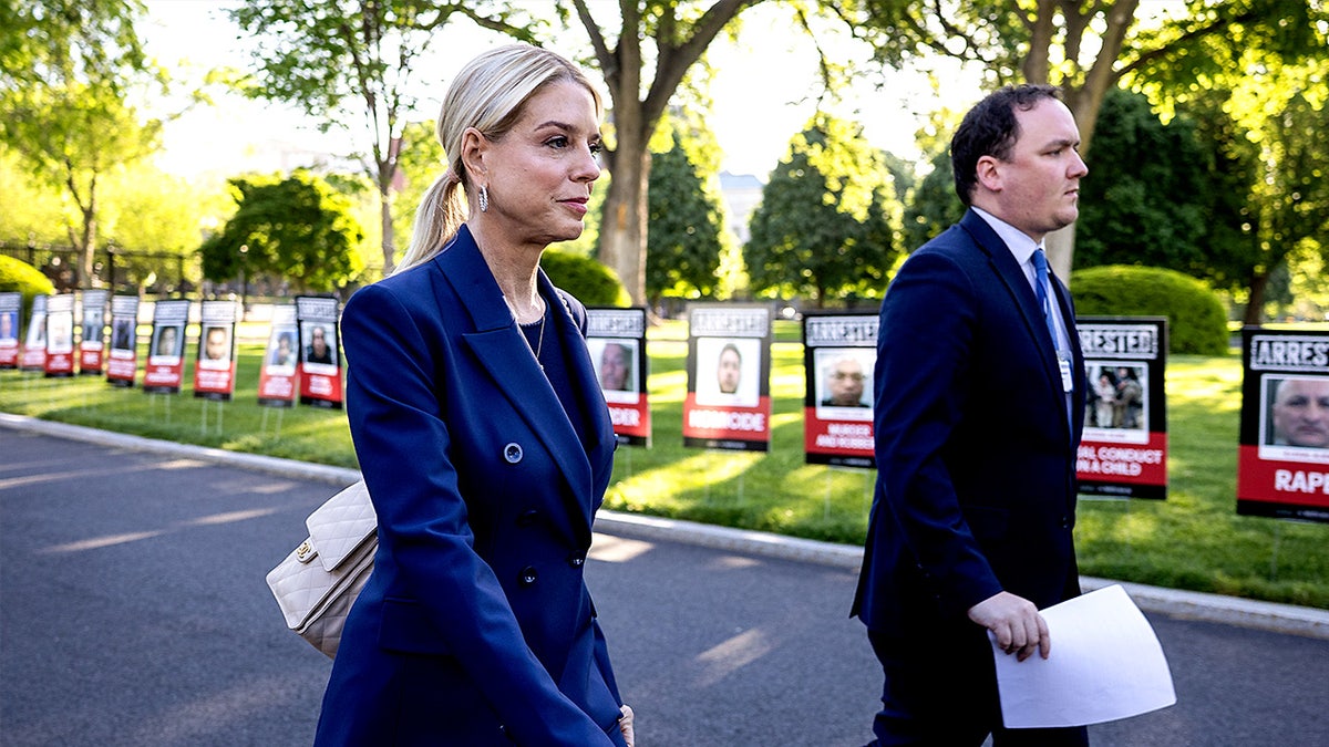Attorney General Pam Bondi walks past images displayed outside the White House in Washington, D.C., showing people alleged to be illegal immigrants arrested for crimes.
