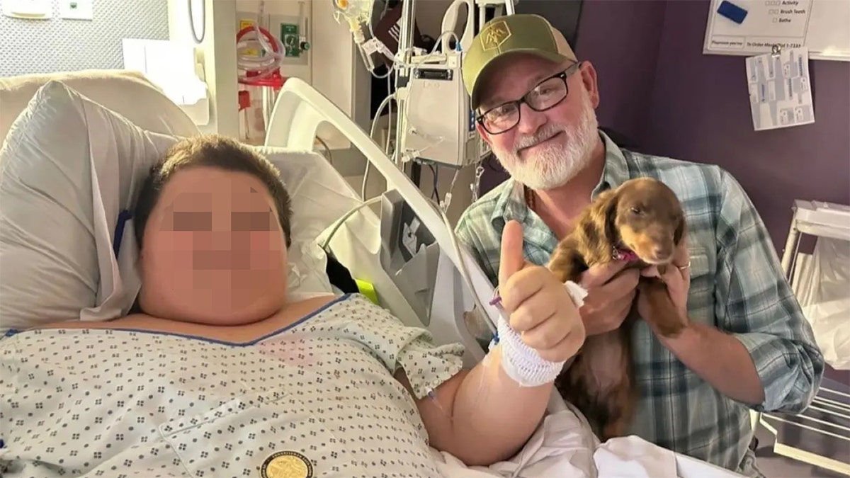 Van Orden crouches by 11-year-old boy's hospital bed holding a puppy