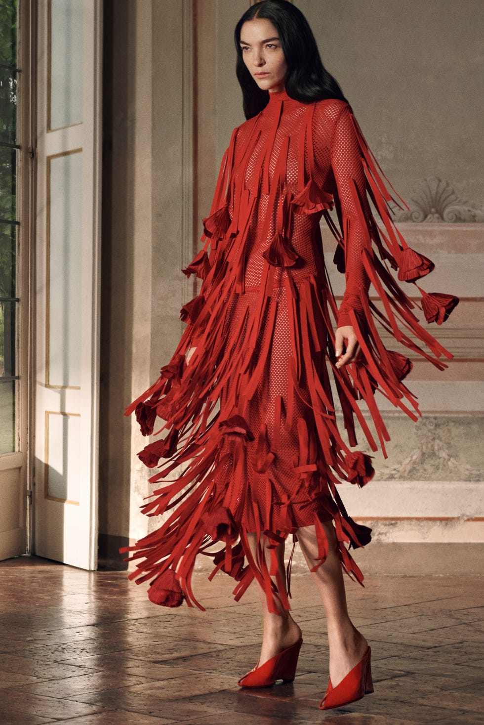 fashion model showcasing a striking red dress with fringe details